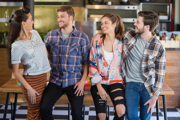 Lachende vrienden leunend op tafel in restaurant — Stockfoto