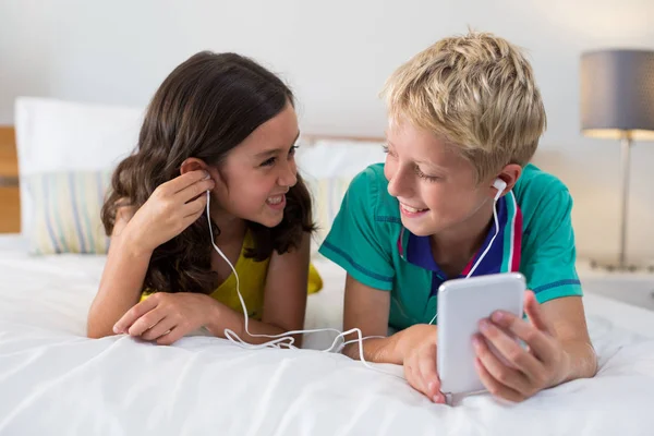 Siblings listening to music while using phone — Stock Photo, Image