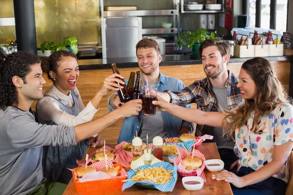 Vrolijke vrienden roosteren bierflesjes in pub — Stockfoto