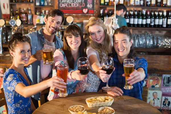 Портрет счастливых друзей, держащих напитки в баре — стоковое фото