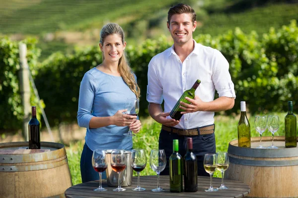 Friends holding wineglass and bottle by table — Stock Photo, Image