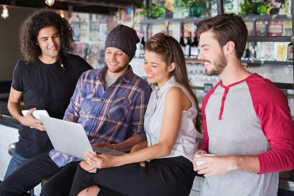 Groep vrienden met behulp van laptop in restaurant — Stockfoto