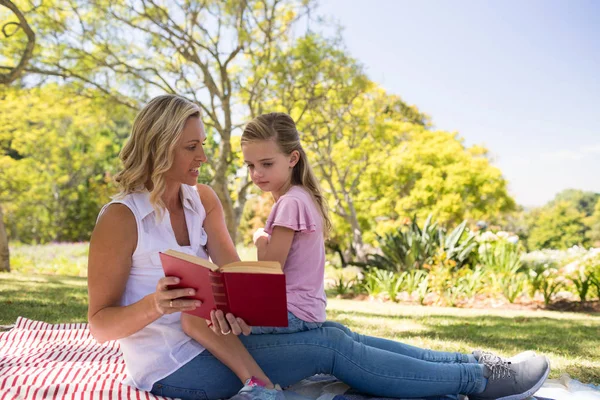 Mãe e filha lendo romance no parque — Fotografia de Stock