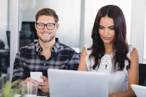 Businessman sitting with female colleague at office — Stock Photo, Image