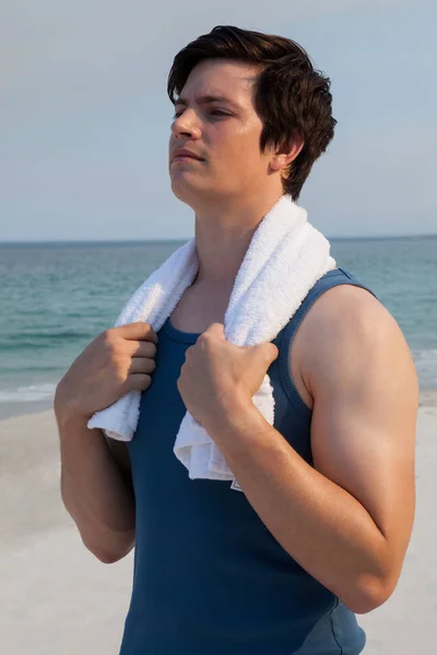 Продуманий чоловік з рушником, що стоїть на пляжі — стокове фото