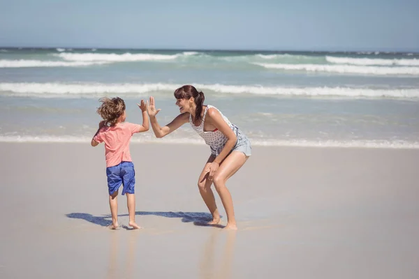 Boy giving high five to mother on shore — Stock Photo, Image