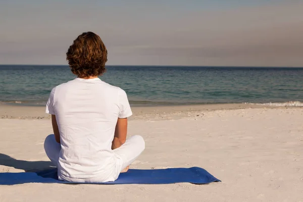 Vista trasera del hombre meditando en la playa —  Fotos de Stock