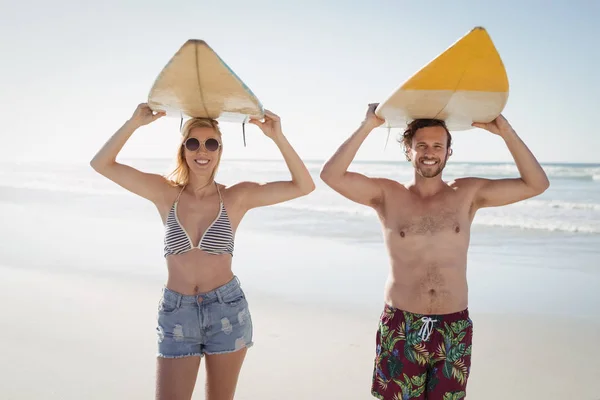 Pareja llevando tabla de surf en la playa — Foto de Stock