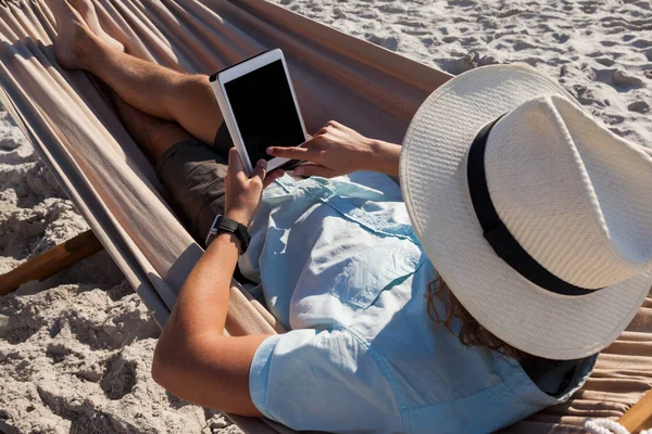 Muž, relaxaci v houpací síti a používání tabletu — Stock fotografie