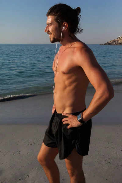 Мускулистый человек, смотрящий на море с пляжа — стоковое фото
