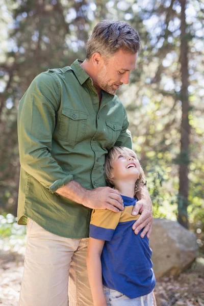 Father and son looking at each other in forest — Stock Photo, Image