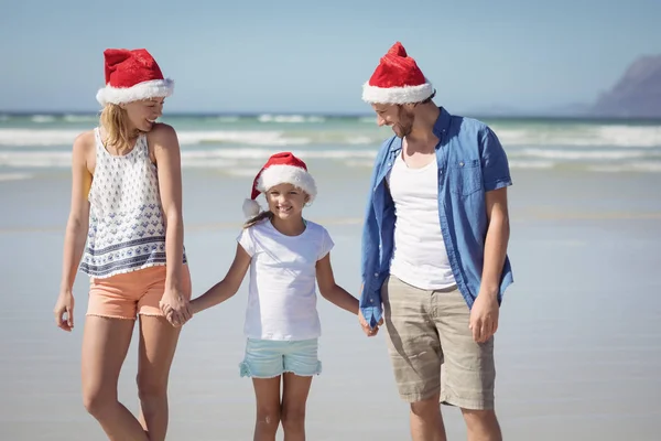 Family wearing Santa hat while standing at beach — Stock Photo, Image