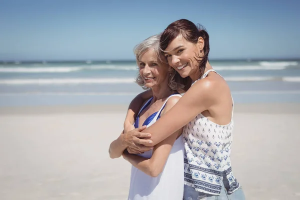 Donna che abbraccia sua madre in spiaggia — Foto Stock