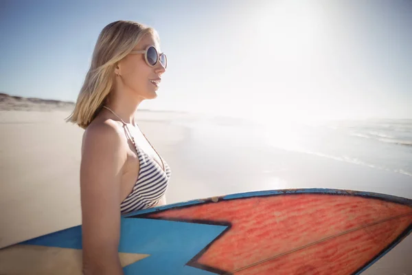 Frau hält Surfbrett am Strand — Stockfoto