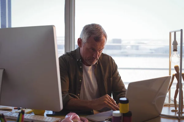 Серьезный бизнесмен, работающий на ноутбуке за столом — стоковое фото