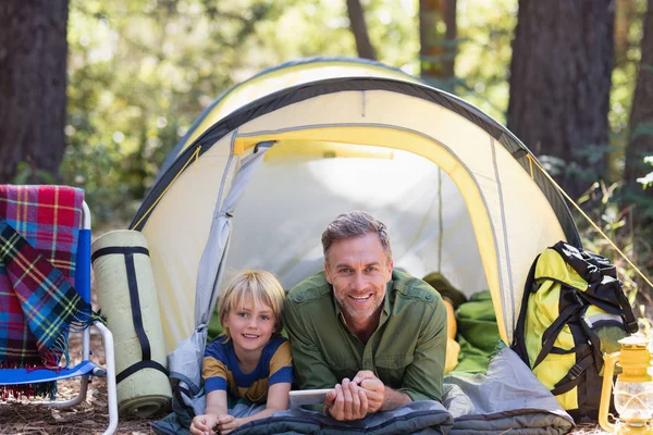 Far och son med tabletten vila i tältet — Stockfoto