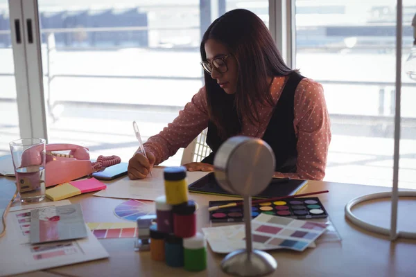 Empresária escrevendo no papel no escritório criativo — Fotografia de Stock