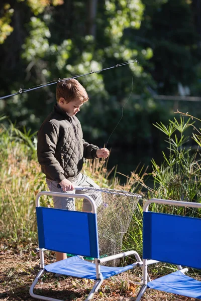 Niño sosteniendo red de pesca por sillas — Foto de Stock