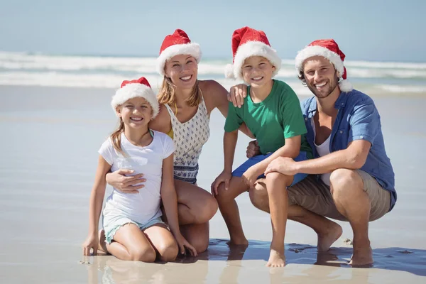 Famiglia che indossa il cappello di Babbo Natale in spiaggia — Foto Stock