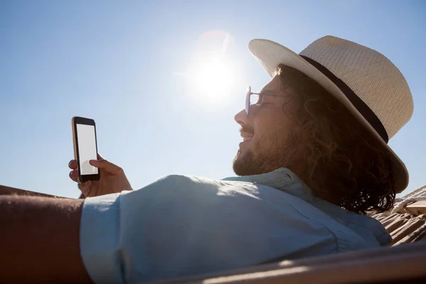 Hombre relajándose en la hamaca y usando el teléfono —  Fotos de Stock