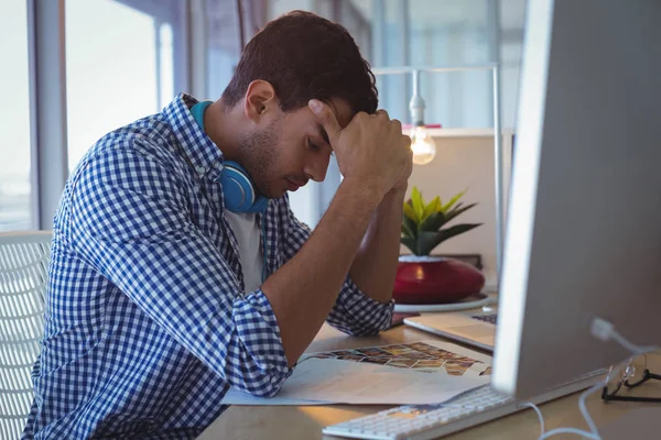 Designer mit Kopf in der Hand sitzend — Stockfoto