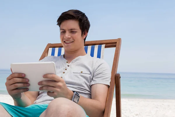 Güneşlenme üzerinde oturan ve tablet kullanarak adam — Stok fotoğraf