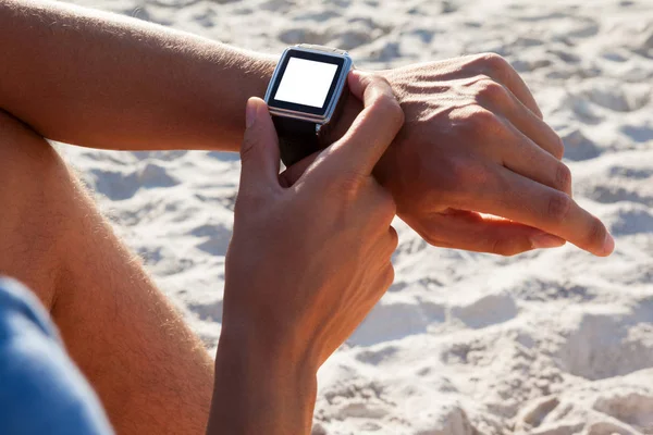 Homme vérifiant sa smartwatch sur la plage — Photo