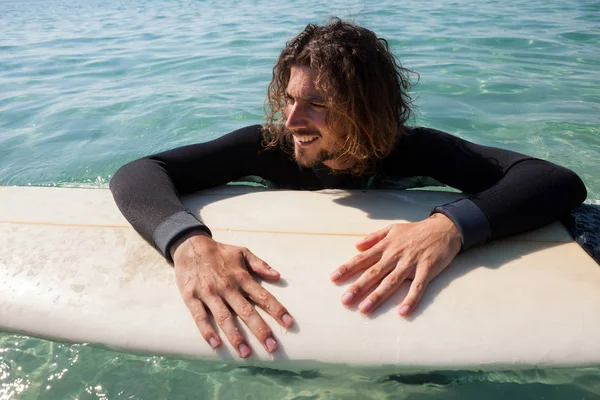 Surfista apoyado en tabla de surf en el mar —  Fotos de Stock