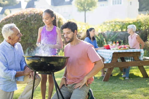 Père et grand-père regardant pendant que la fille prépare le barbecue — Photo