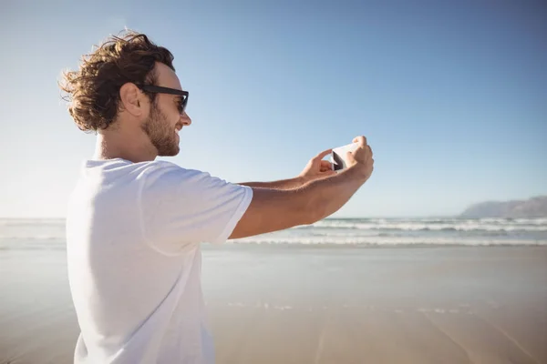 Człowiek biorąc selfie przeciw błękitne niebo na plaży — Zdjęcie stockowe