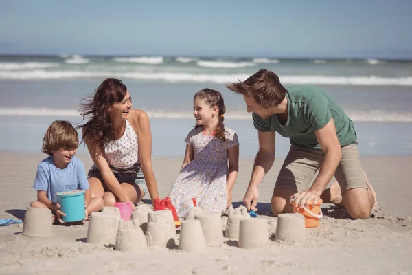 Alegre família fazendo castelo de areia na praia — Fotografia de Stock