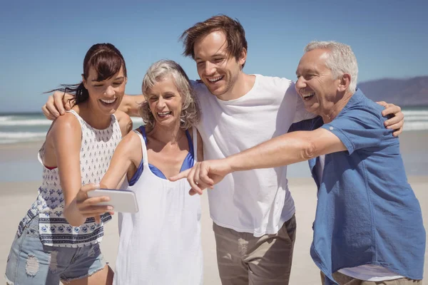 Família alegre olhando para o telefone móvel — Fotografia de Stock