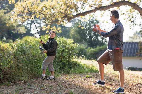Father photographing son in forest — Stock Photo, Image