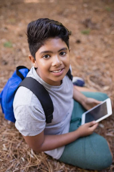 Boy sitting with tablet PC in forest — Stock Photo, Image