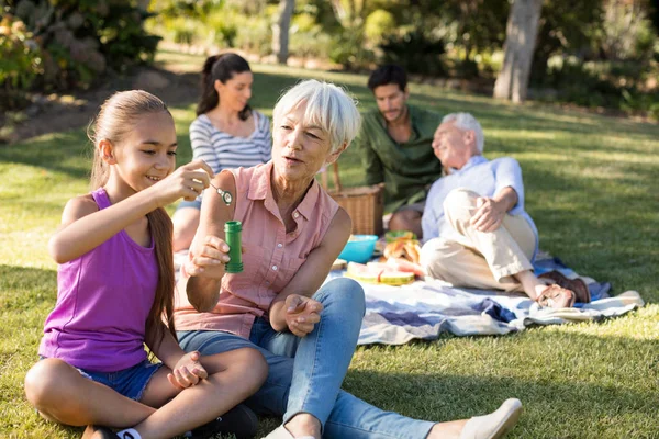 Nonna guardando nipote soffiando bolle — Foto Stock