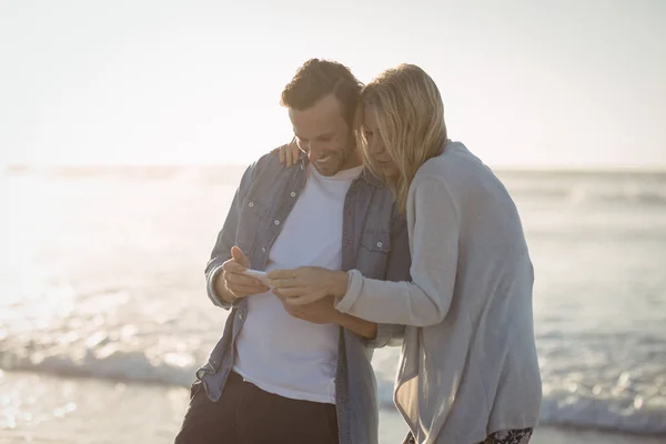 Paar benutzt Handy am Strand — Stockfoto