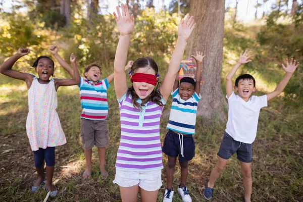 Amigos con los ojos vendados chica animando en el bosque — Foto de Stock