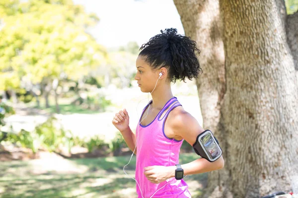 Female jogger listening to music while jogging — Stock Photo, Image