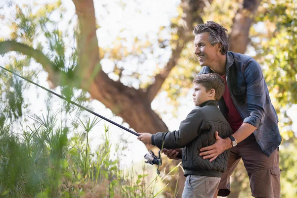 Padre ayudar a hijo mientras pesca en el bosque —  Fotos de Stock