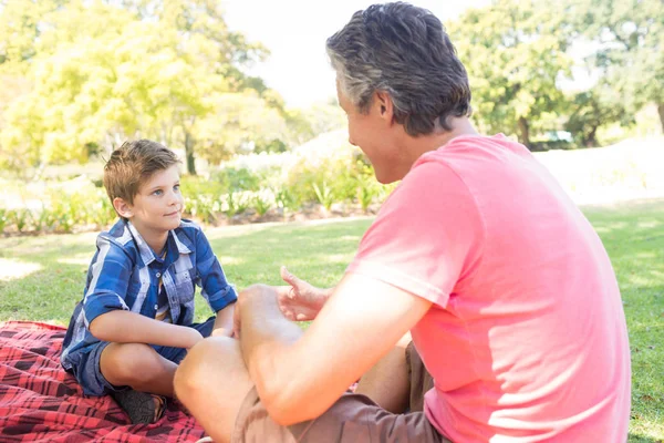 Pai falando com filho no piquenique no parque — Fotografia de Stock