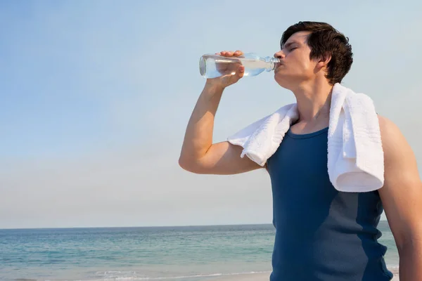 Homem bebendo água de garrafa na praia — Fotografia de Stock