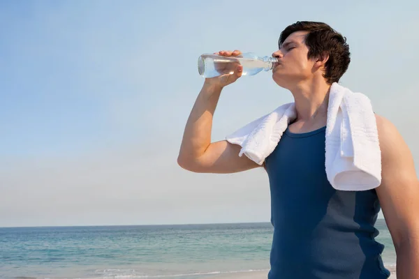 男は、ビーチでボトルから水を飲む — ストック写真