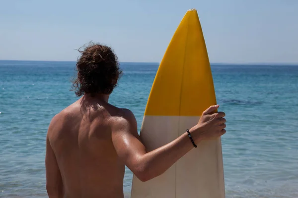 Серфер с доской для серфинга смотрит в море — стоковое фото