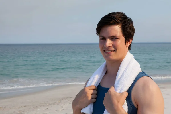 Muž, který stojí na pláži s ručníkem kolem krku — Stock fotografie