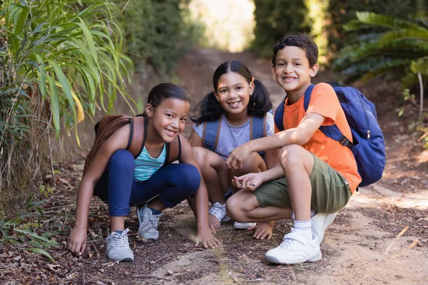 Friends crouching on field at natural parkland — Stock Photo, Image