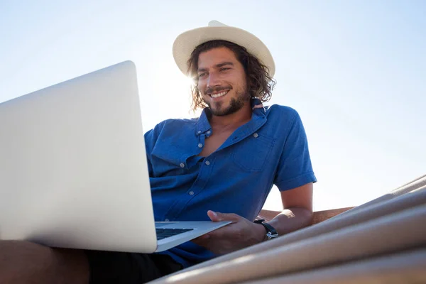 Człowiek za pomocą laptopa na hamak na plaży — Zdjęcie stockowe