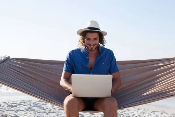 Man met laptop terwijl op de hangmat op strand — Stockfoto