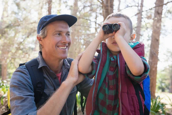 Homem assistindo filho olhando através de binóculos — Fotografia de Stock