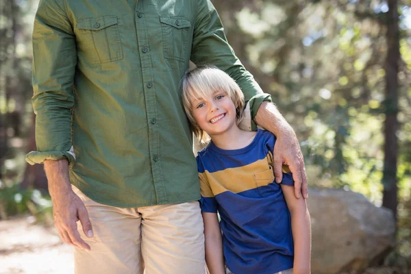 Boy standing with father on sunny day in forest — Stock Photo, Image