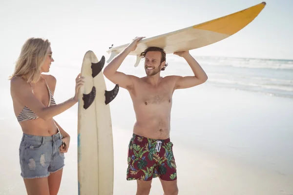 Paar hält Surfbrett am Strand — Stockfoto